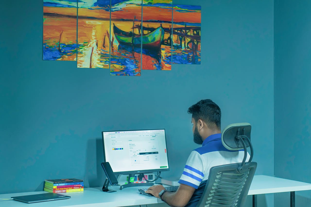 A man working on a desktop computer at home office with vibrant wall art.